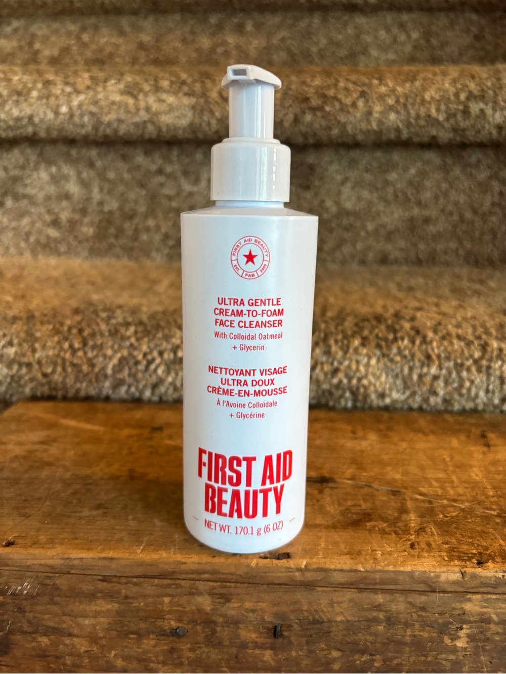 First Aid Beauty White Bottle with Red Logo and Text